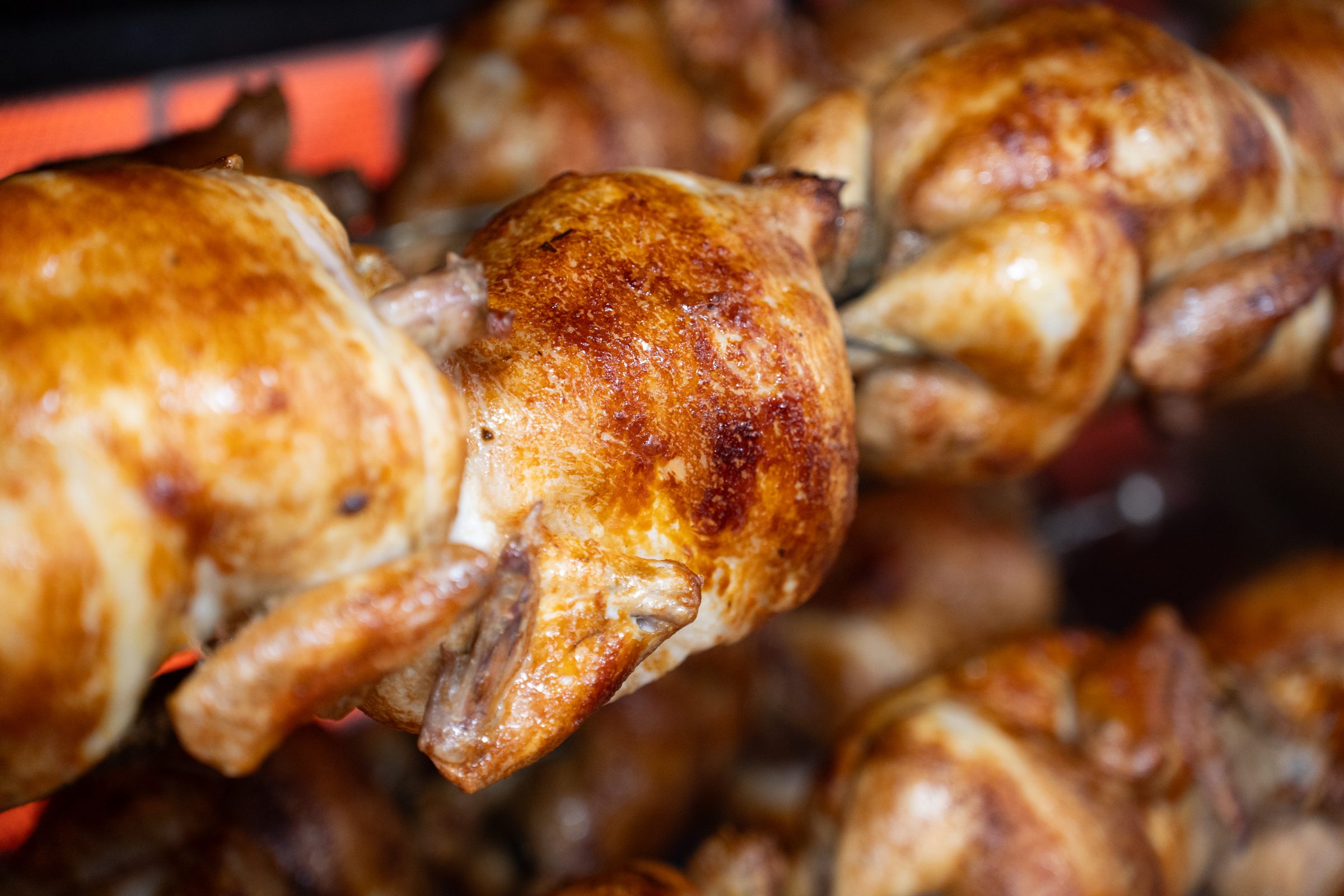 Pollos asados dorados girando en el asador